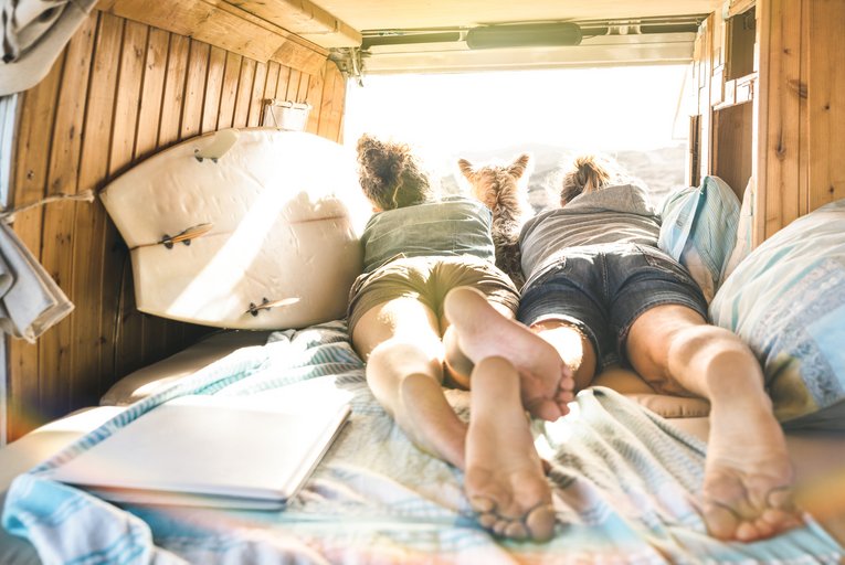 Pärchen liegt mit Surfboard in Camper